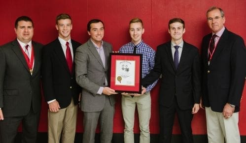 Four young men holding an award certificate together.