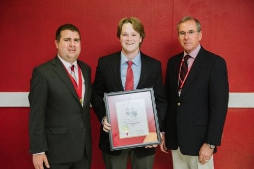 Three men holding an award certificate together.