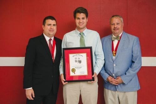 Three men holding an award certificate.