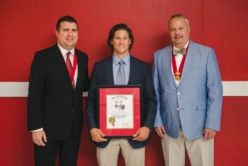 Three men posing with an award certificate.