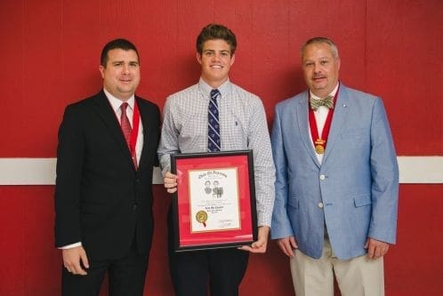 Three men holding an award certificate together.