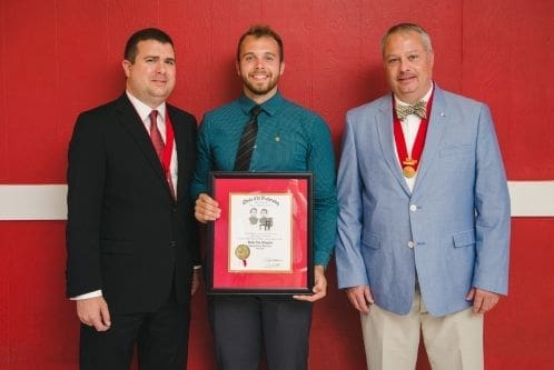 Three men holding an award certificate together.