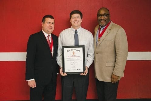 Three men celebrating an award presentation.