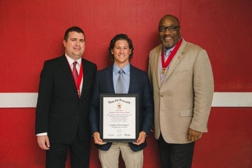 Three men posing with an award certificate.