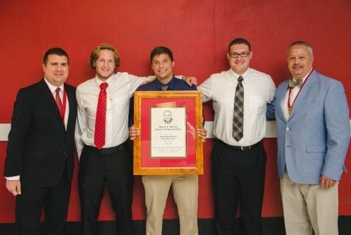 Group celebrating award with framed certificate.