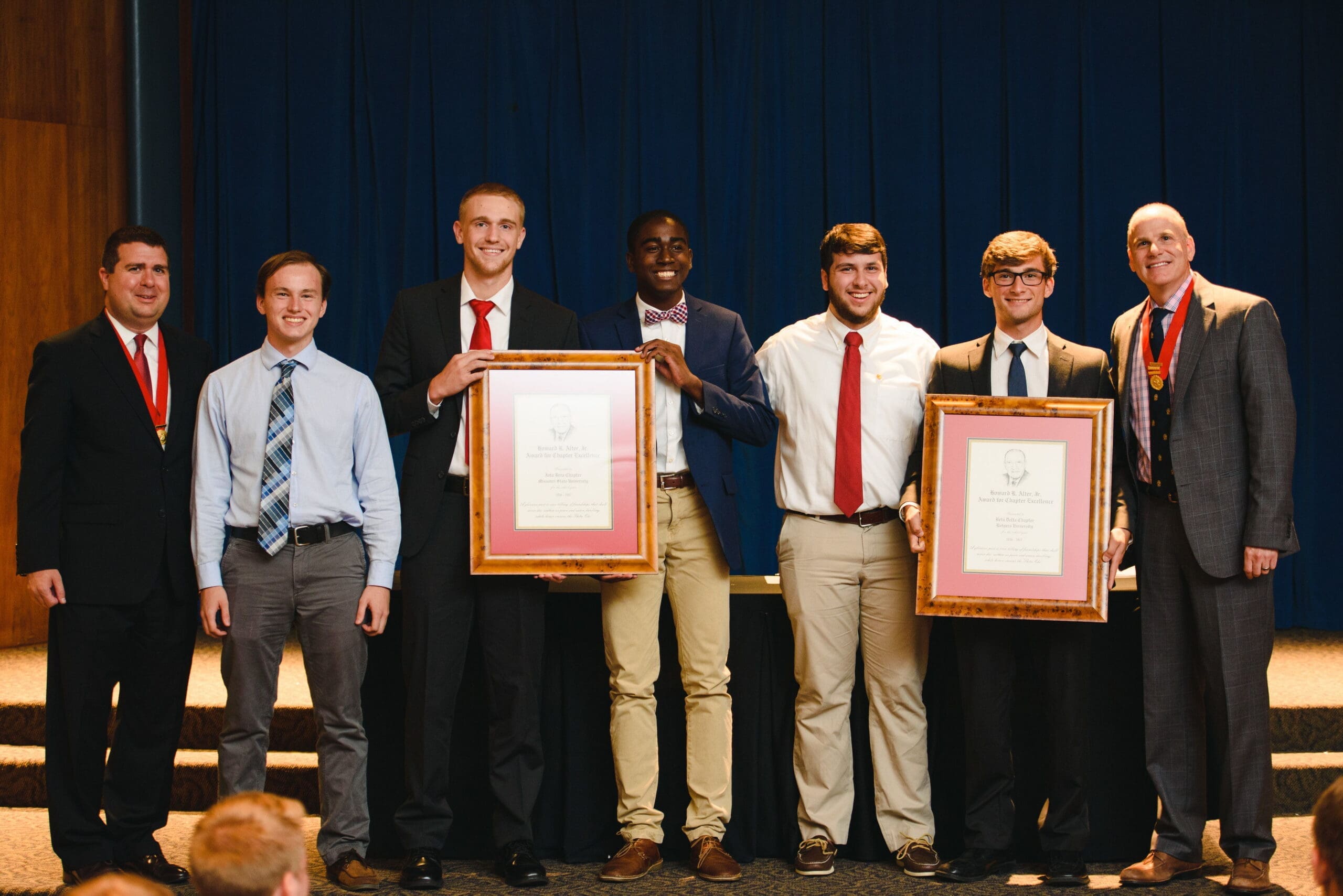 Students holding achievement awards at graduation ceremony.