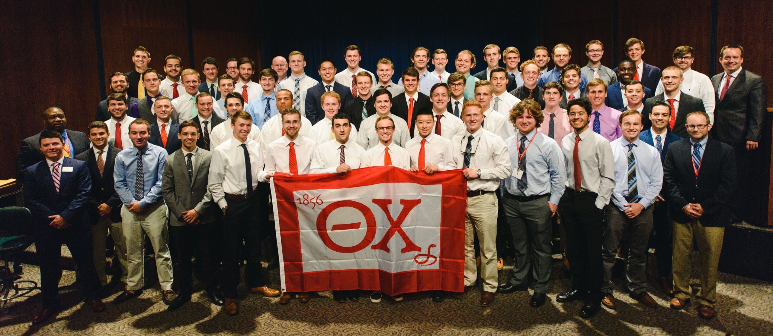 Group of fraternity members holding a flag.