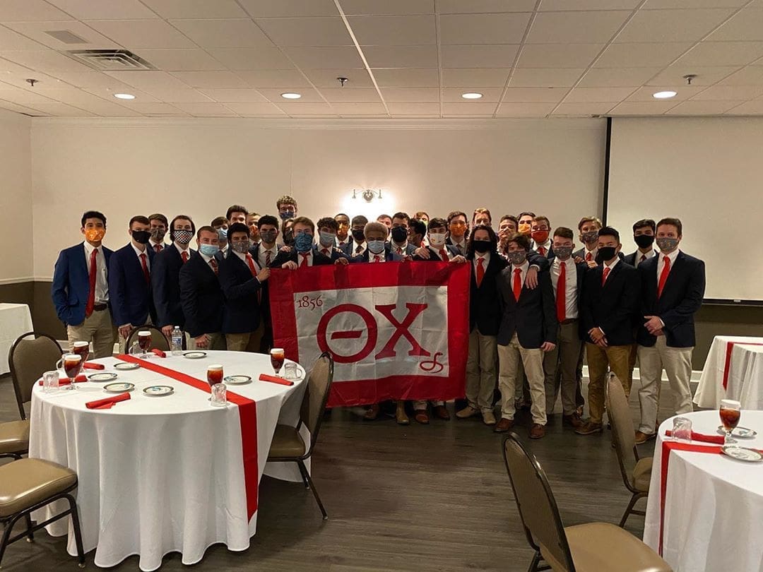 Group photo of fraternity members holding flag.