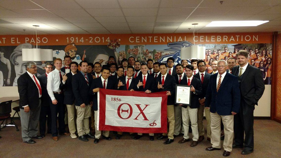 Group photo of fraternity members with flag.