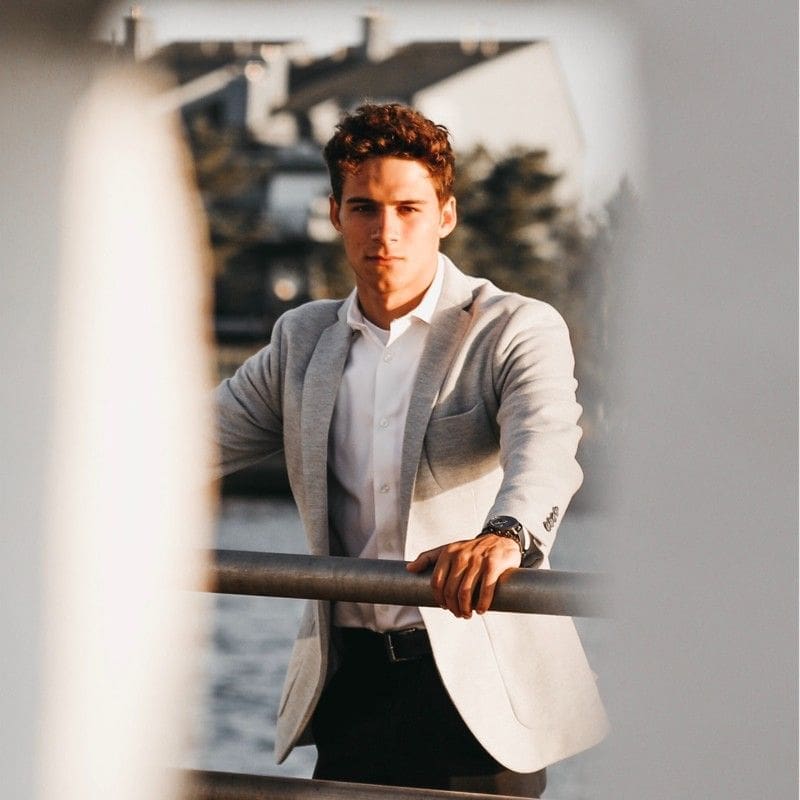 Man in a gray blazer by the water.