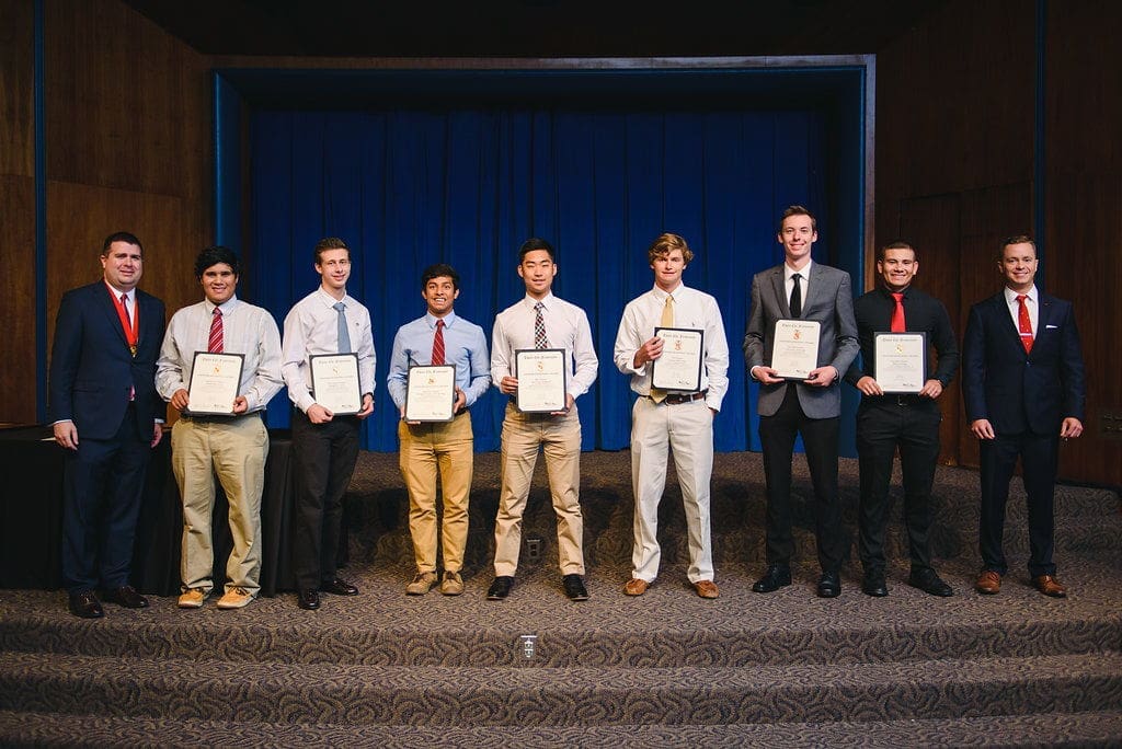 Students proudly displaying achievement certificates on stage.