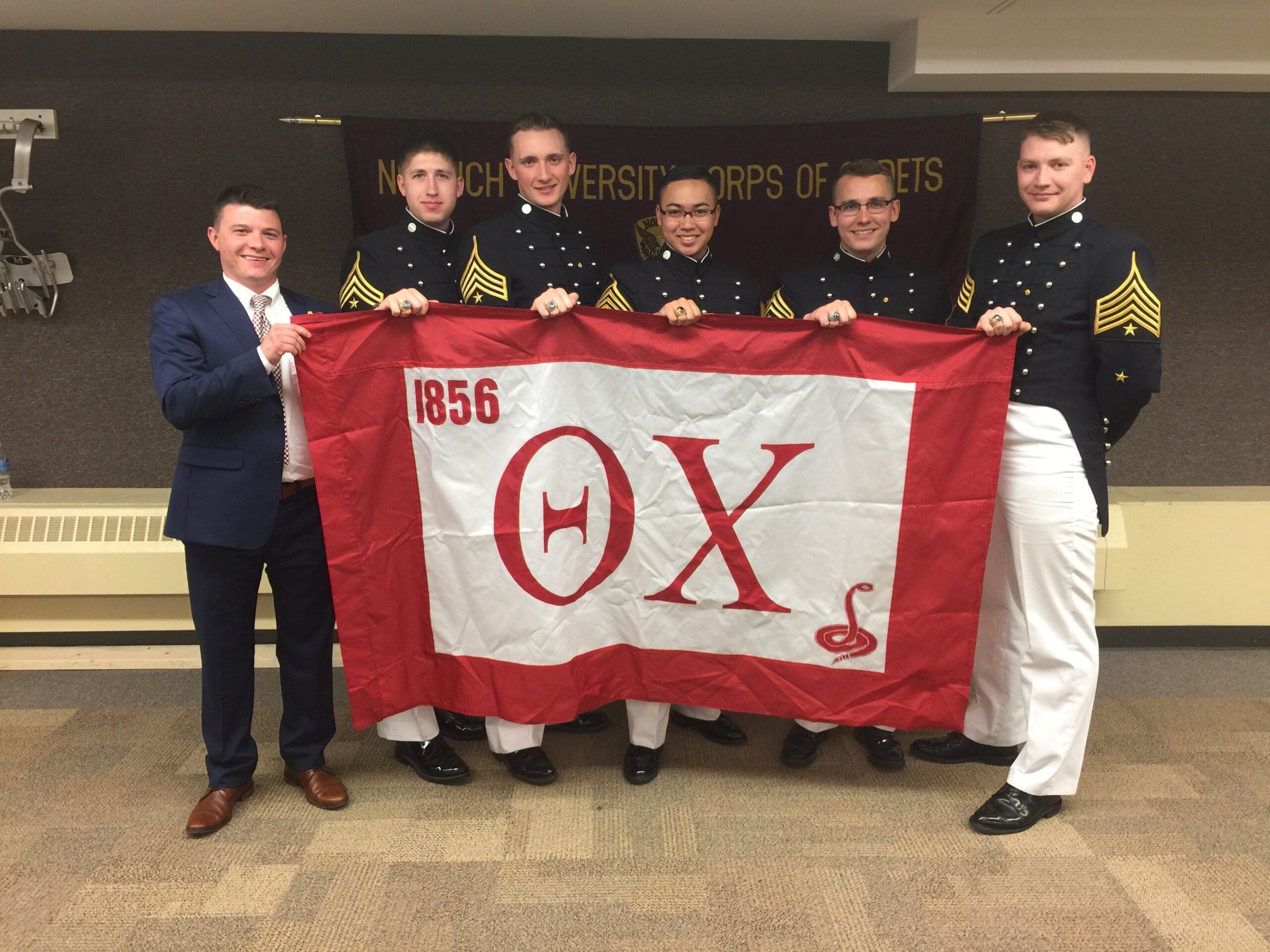 Cadets holding a flag at military event.