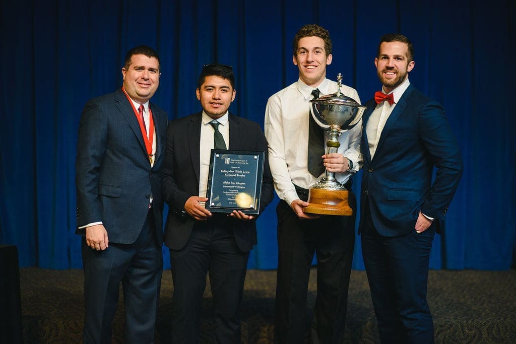 Award ceremony with four men holding trophies.