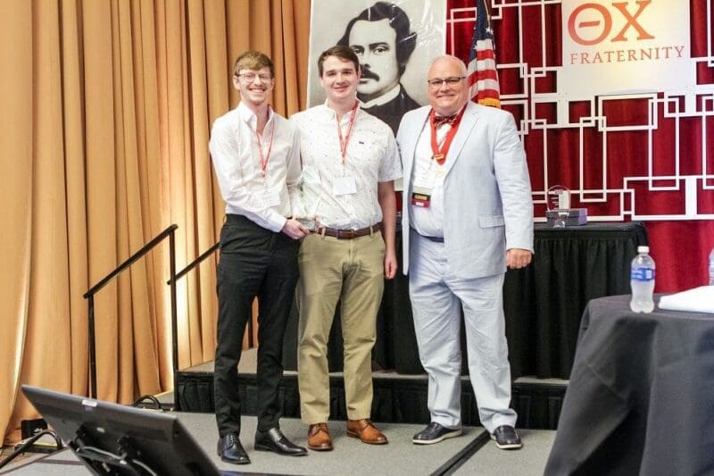 Young men receiving award at conference event.