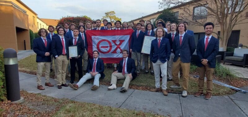 Group photo of fraternity members with flag.