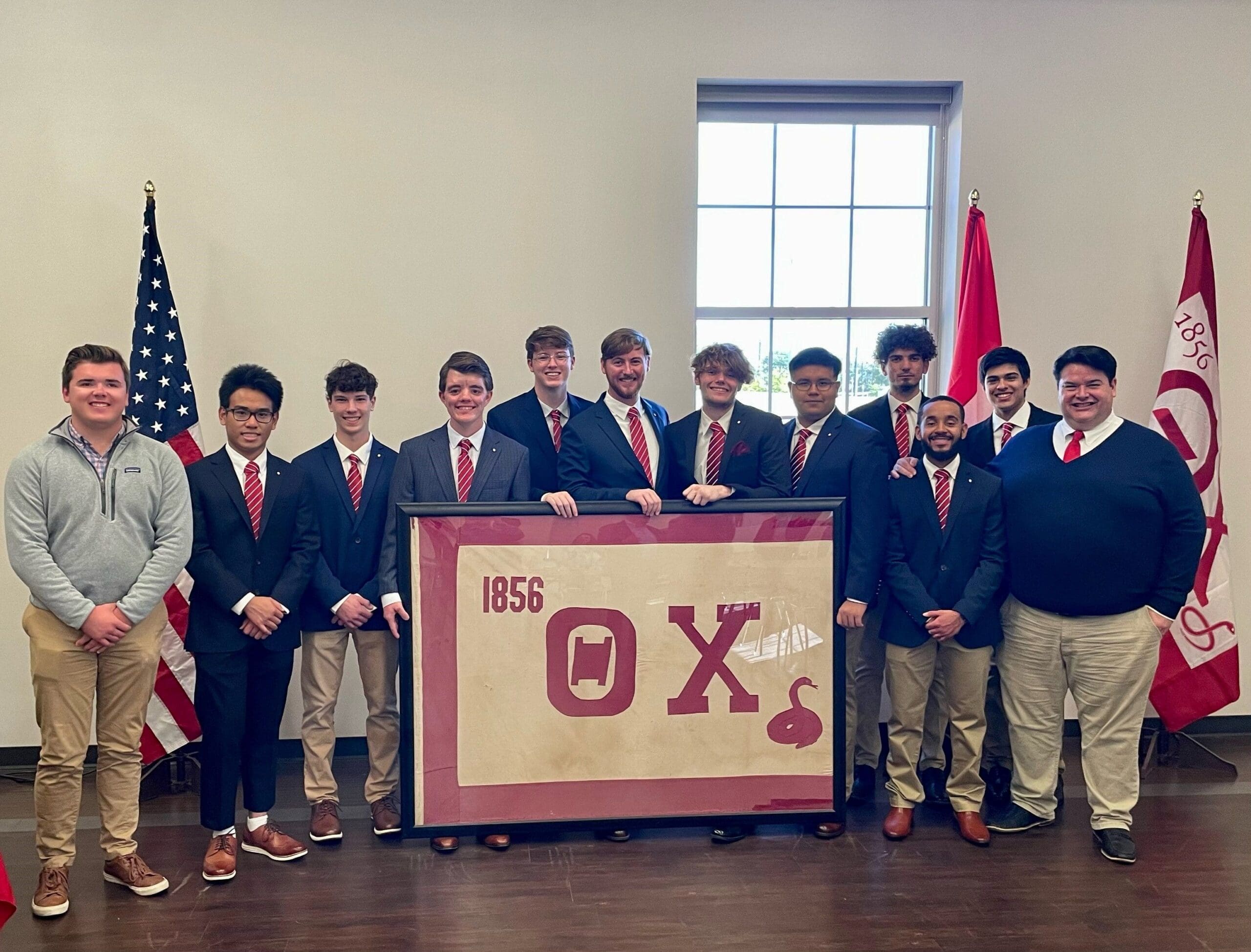 Group of fraternity members with banner and flags.