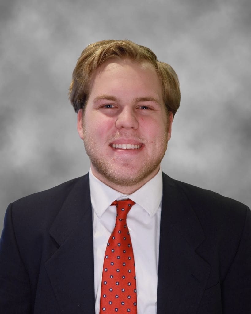 Smiling man in suit with red tie.