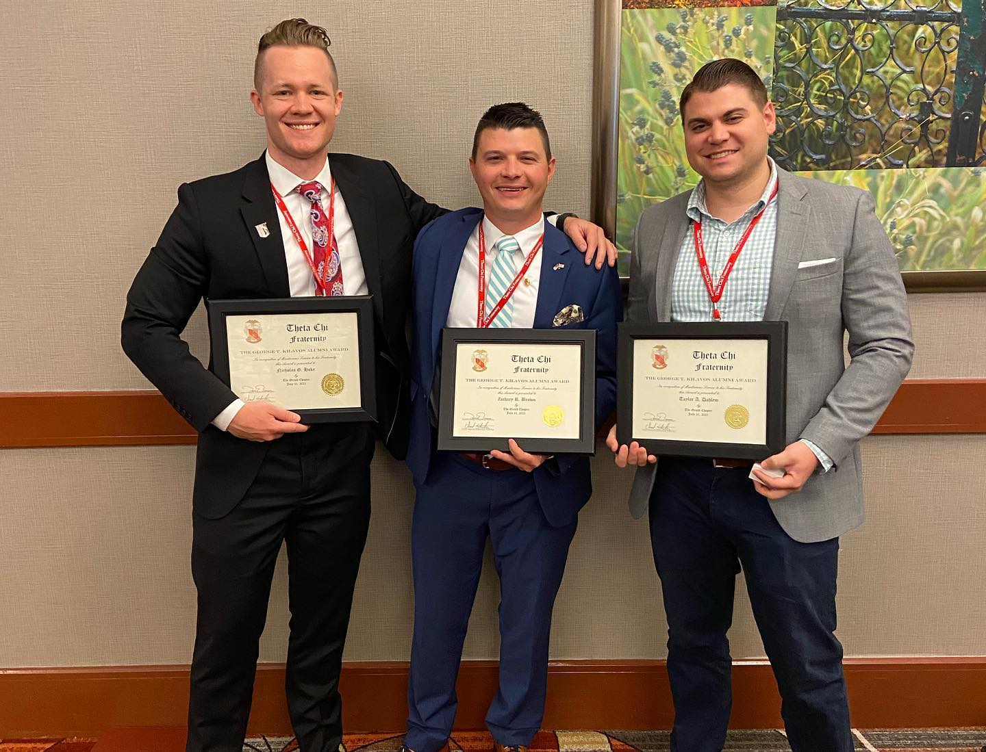 Three men holding achievement certificates at an event.