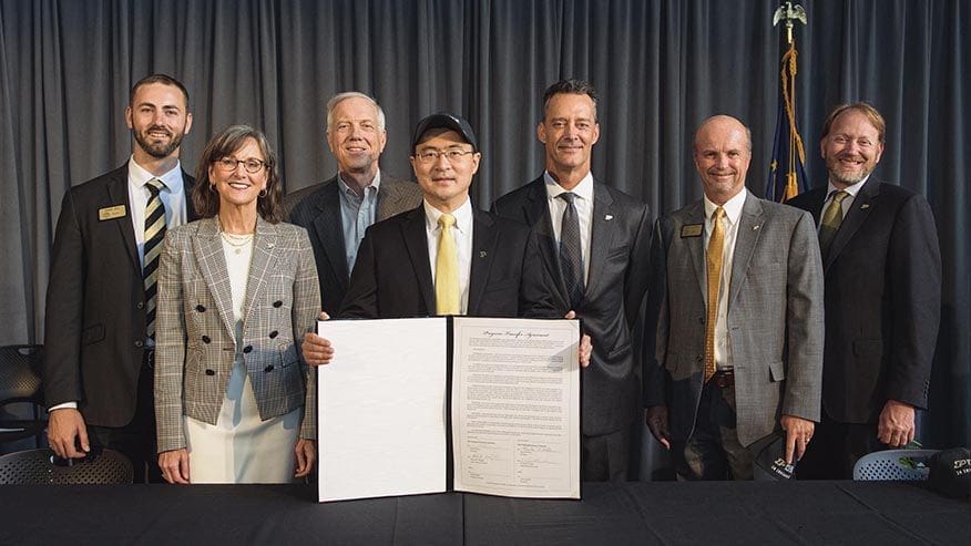 Business leaders signing partnership agreement at event.