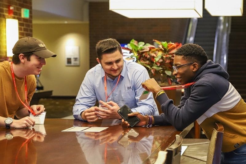 NHPW 2020 - Day 3 Three men engaged in conversation at a conference.