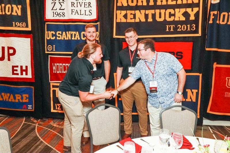 Networking event with attendees shaking hands and socializing.