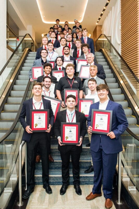 Group of award winners on staircase holding certificates.