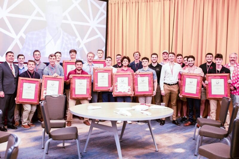 Group of award winners holding framed certificates.