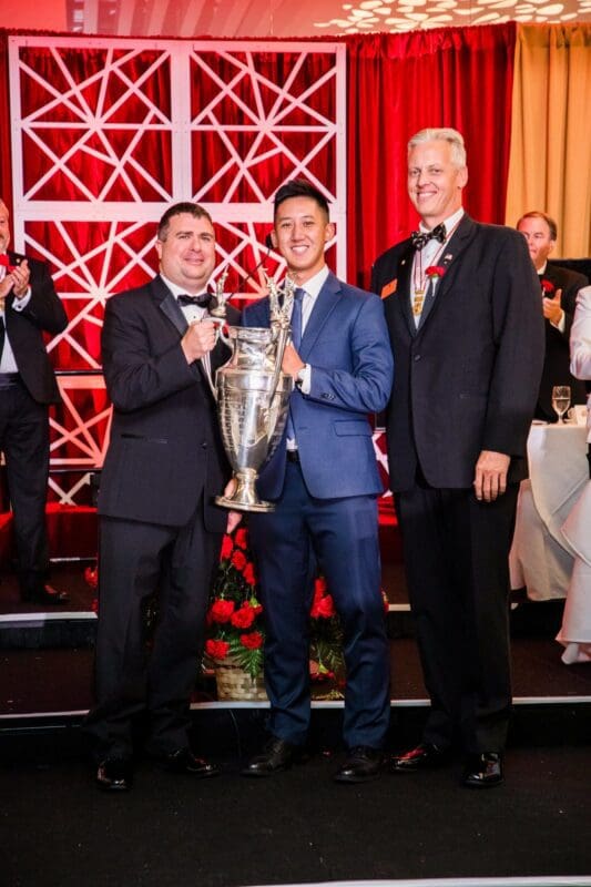 Award ceremony with trophy presentation and smiling winners.