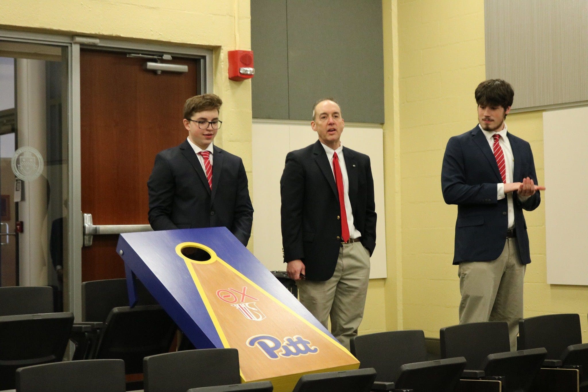 Students presenting with cornhole board at event.