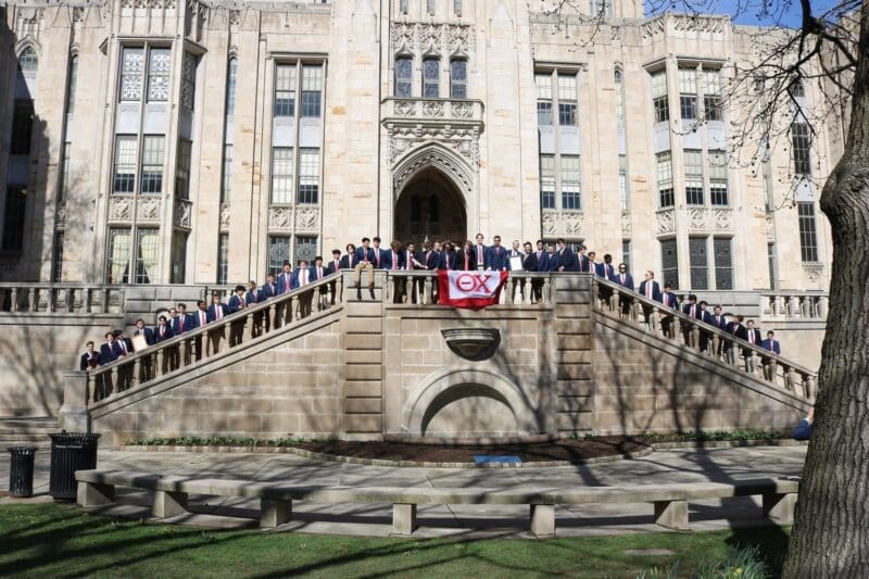 Group of students posing with flag at university.