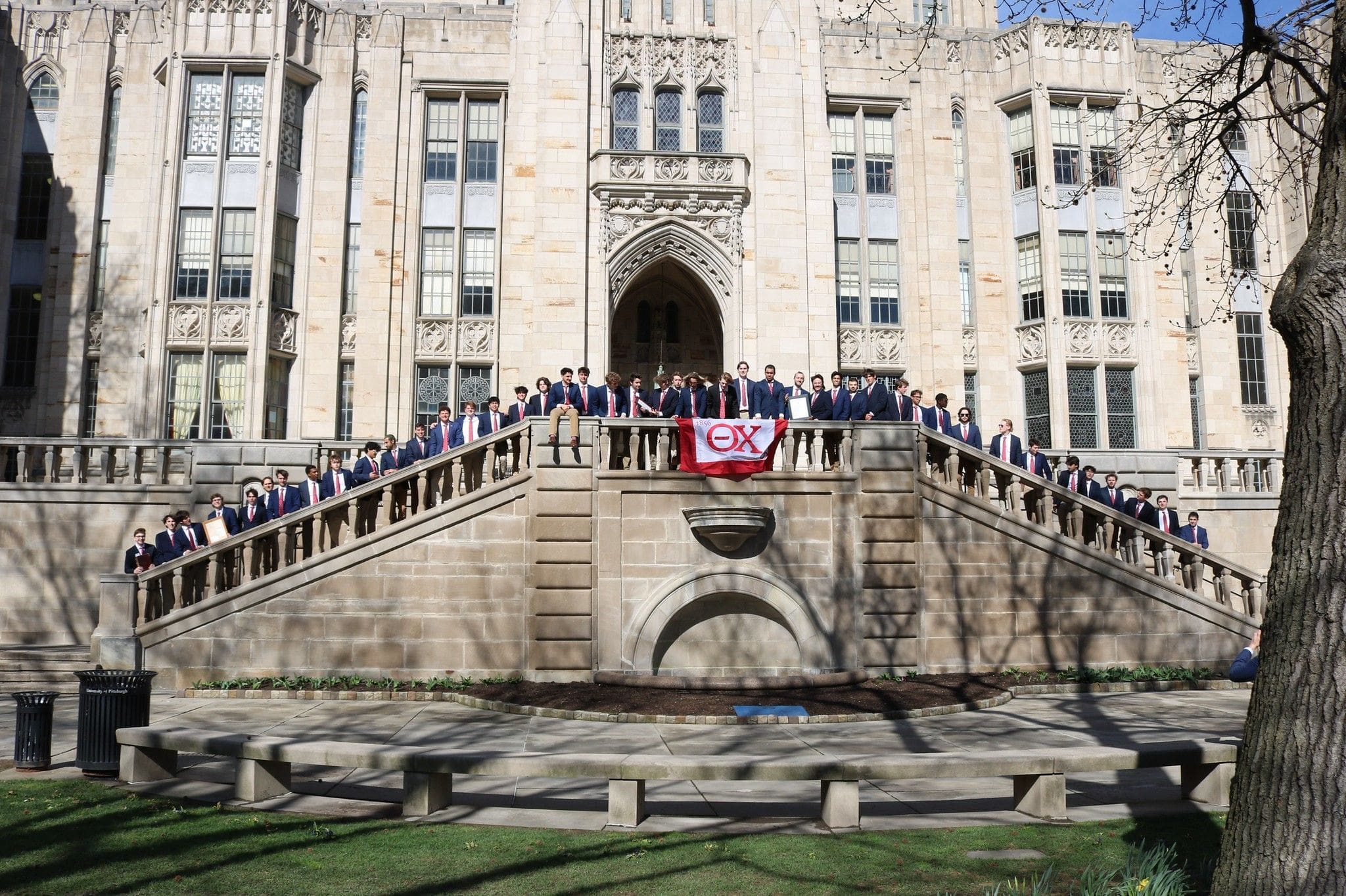 Group of students posing with flag at university.