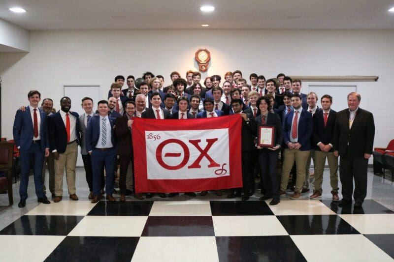 Group photo of fraternity members holding banner.
