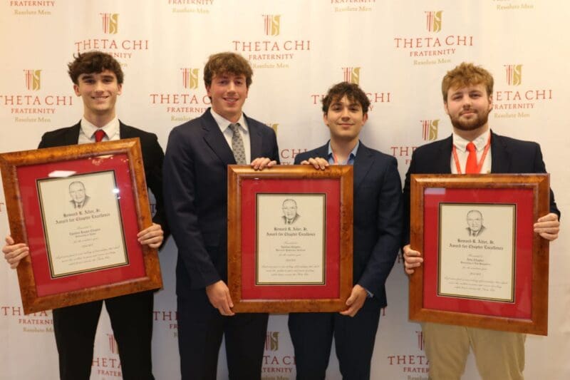 Theta Chi fraternity members holding achievement awards.