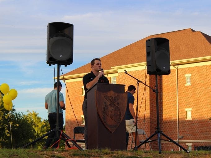 Speaker at outdoor event with sound equipment.