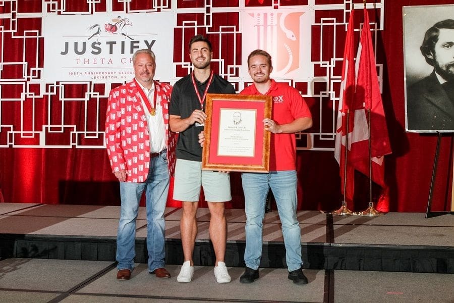 Award ceremony with three men holding a certificate.