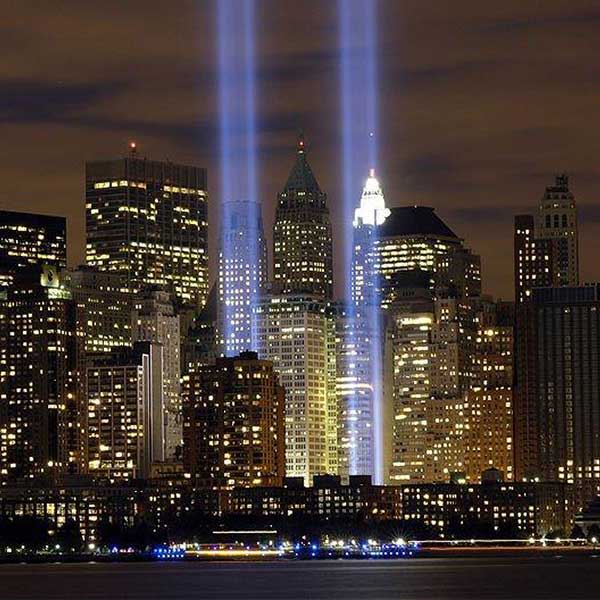 Tribute lights illuminating New York City skyline at night.