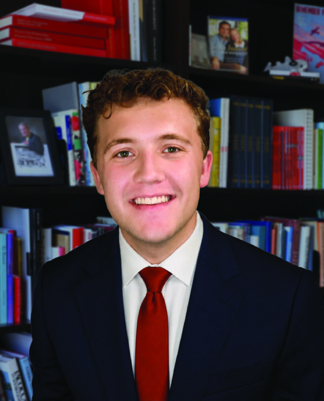 Photo of a man in a suit in front of a bookcase