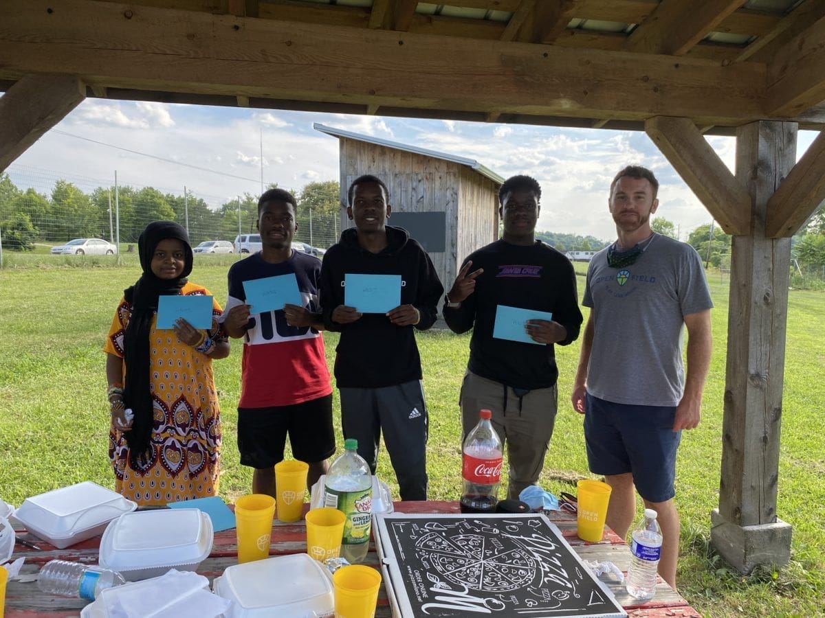 Group of people holding blue cards outdoors.