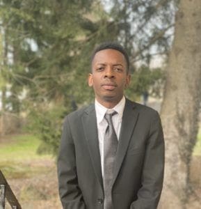 Young man in a suit standing outdoors.