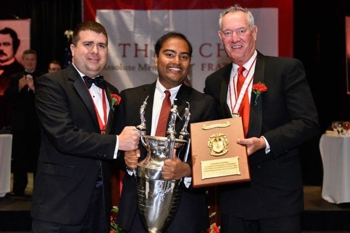 Three men celebrating an award ceremony with trophies.