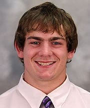 Smiling young man in formal attire with tie.
