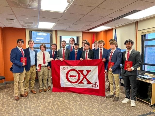 Group of students celebrating with fraternity flag.