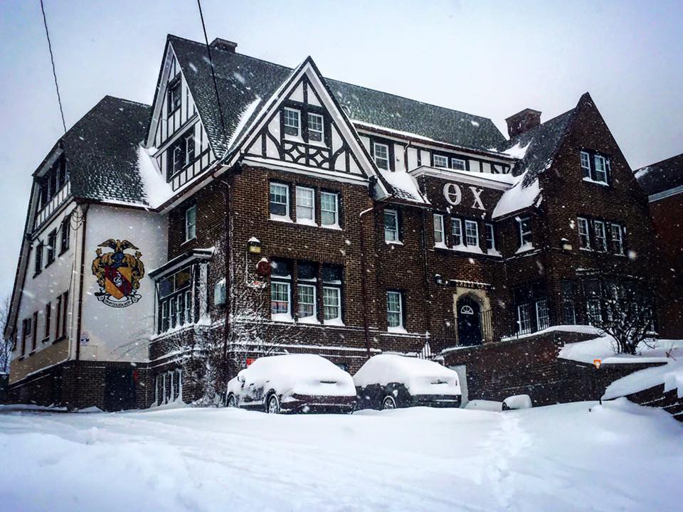 Snow-covered historic building with parked cars.