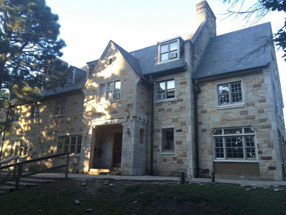 Historic stone mansion with large windows and porch.
