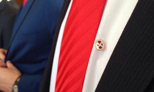 Red tie with gold lapel pin detail.