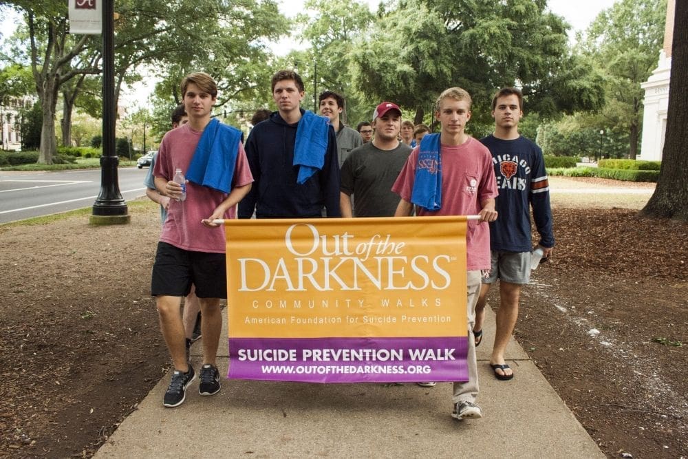 Participants in suicide prevention walk holding banner.