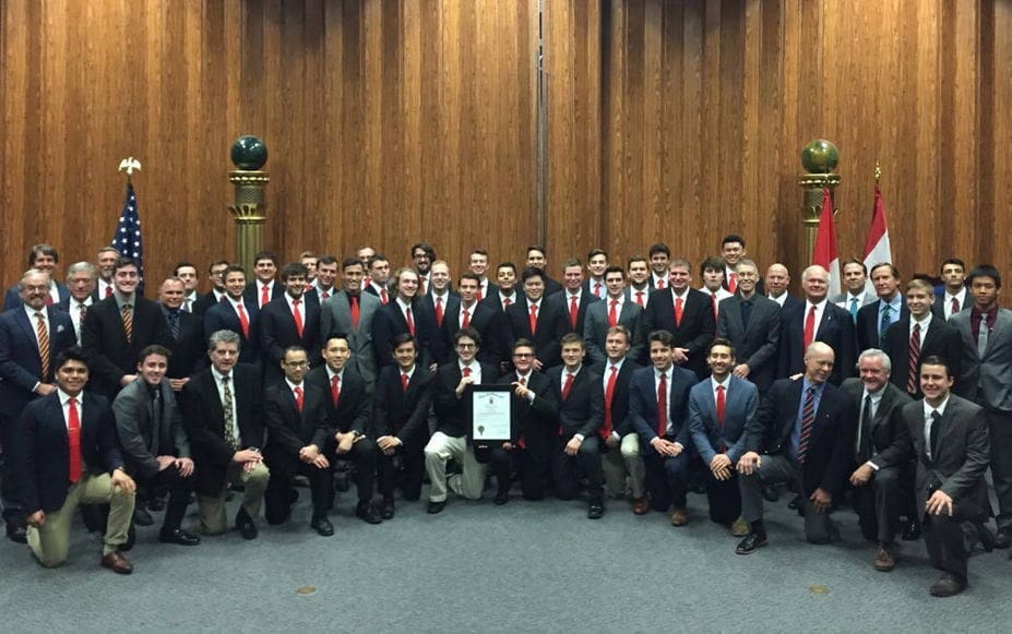 Group photo of men in formal attire with red ties.