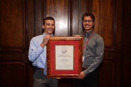 Two men holding framed award certificate proudly.