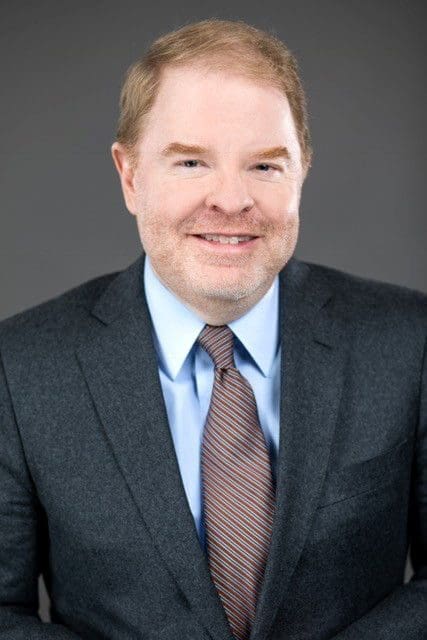 Peter Hans Professional man in suit and tie smiling.