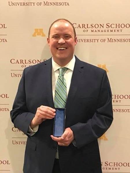 Chad Ellsworth Man holding award at Carlson School of Management event.